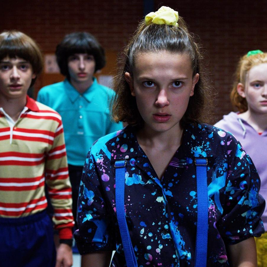 Four kids stand together, looking serious and ready for action. Noah Schnapp, Finn Wolfhard, Millie Bobbie Brown, and Sadie Sink mean business in this still from Stranger Things Season 3.
